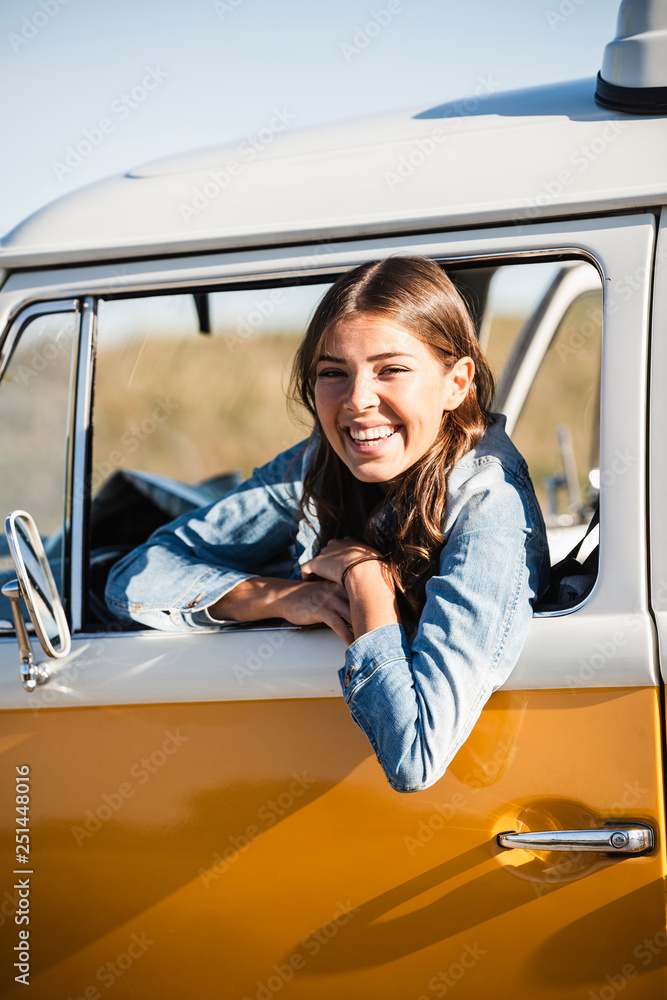 Pretty woman on a road trip with her camper, looking out of car window ...