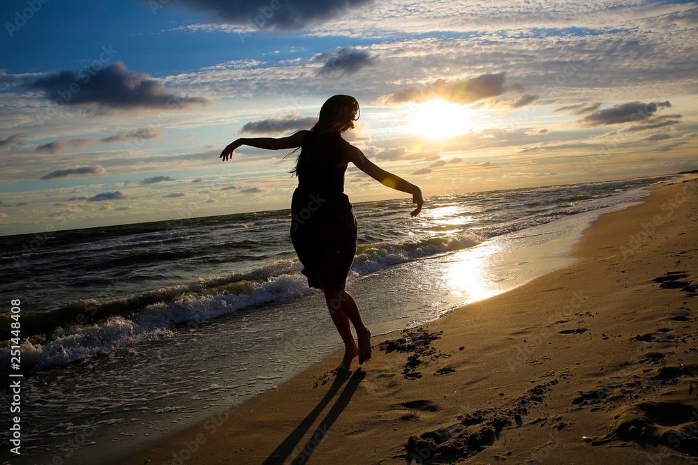 Woman on the sea coast on sunset