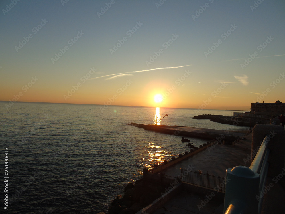 Genova, Italy - 02/14/2019: An amazing caption of the sunset over the sea and the city of Genoa in winter days and great views to the old buildings near the beach coloured by the sun
