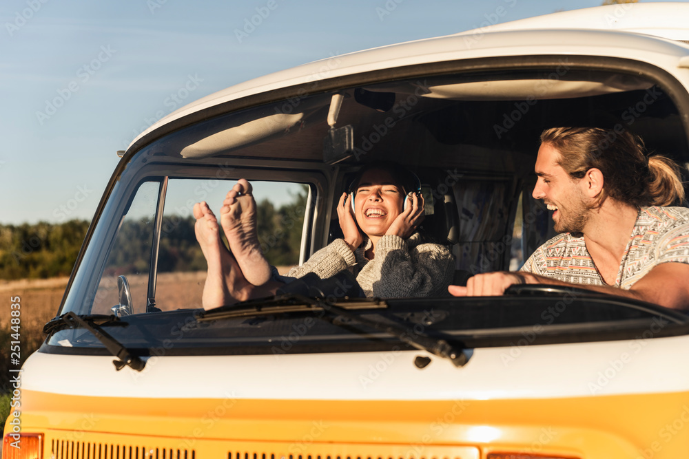 Happy couple sitting in their camper with bare feet up, listening music Happy couple sitting in their camper with bare feet up, listening music