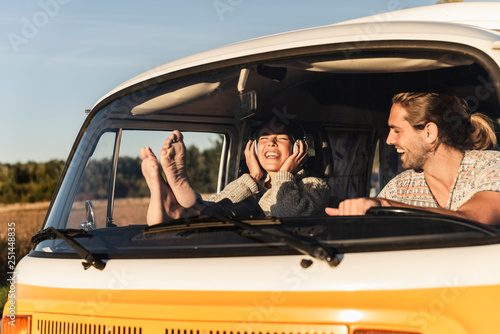 Happy couple sitting in their camper with bare feet up, listening music photo