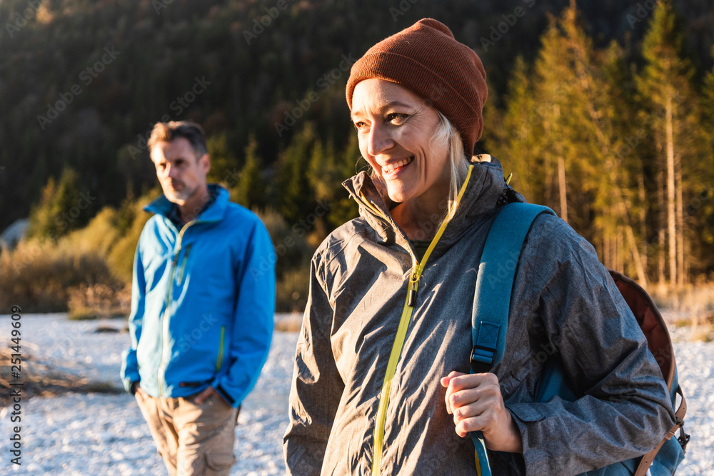 Mature couple hiking at riverside in the evening light Mature couple hiking at riverside in the evening light