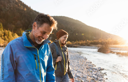 Smiling mature couple at riverside during sunset photo