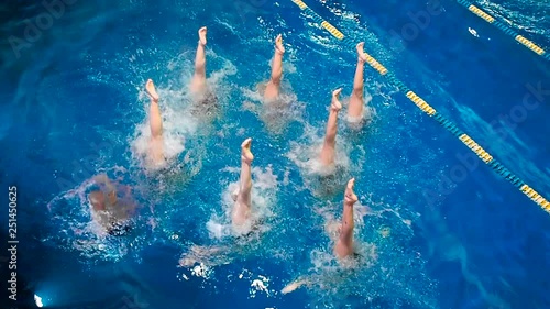 Synchronized swimming. Young girls learn swimming in the pool. Young girls are trained to competitive swimming in the pool. Water team sports, girls synchronized swimming