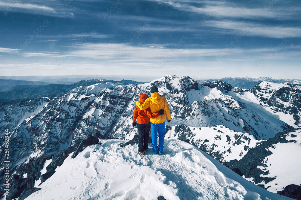 Couple standing at the top of the snow covered mountain Jebel Toubkal, Atlas Morocco