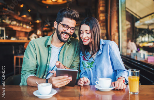 Young couple having fun with tablet in a cafe. Dating, relationships, love, romance, lifestyle, technology