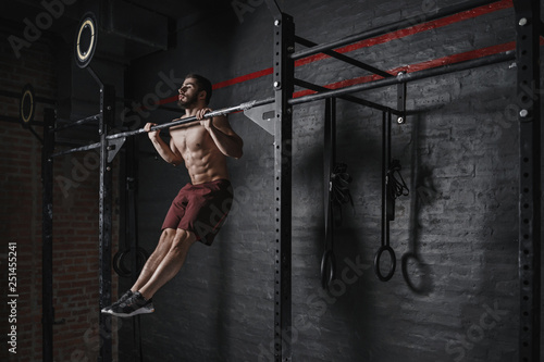 Obraz na plátně Crossfit athlete doing pull-ups at the gym