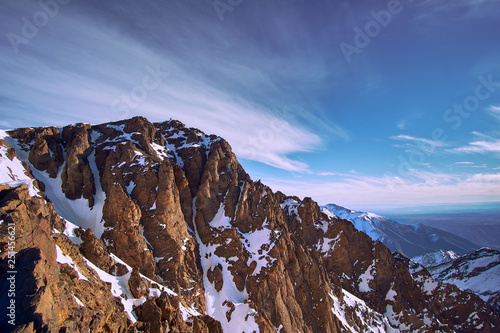 View of rocky wall under the top of snow covered peak of Jebel Toubkal mountain in High Atlas Morocoo photo