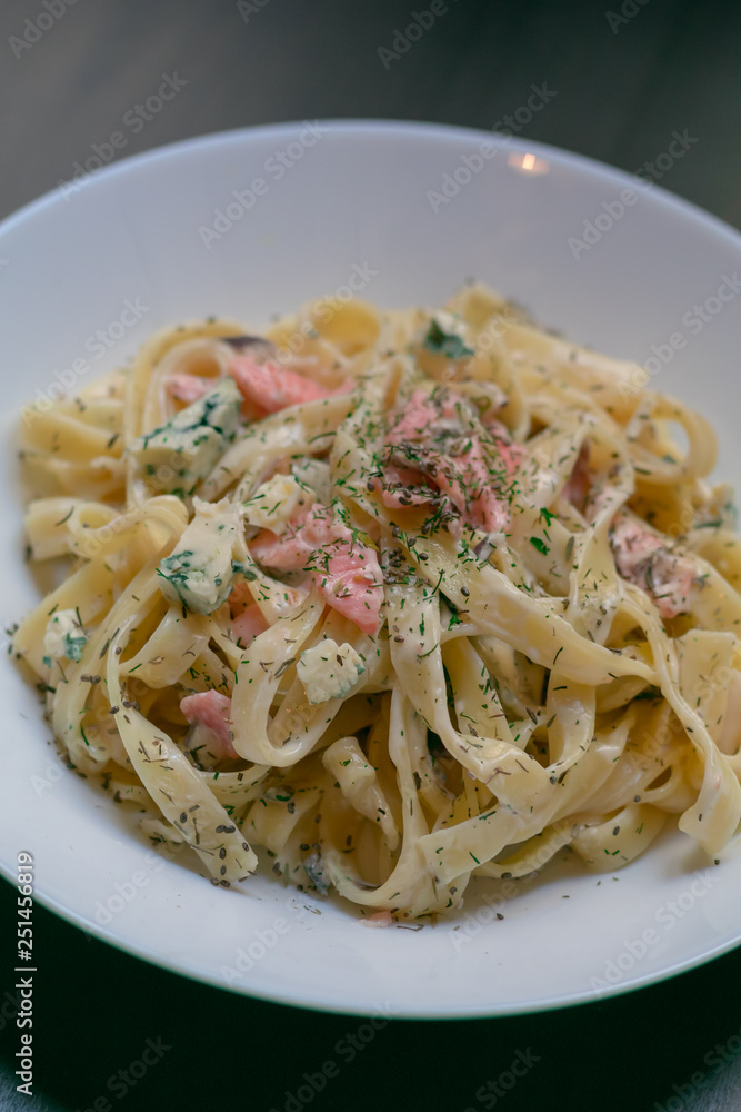 Homemade tagliatelle with salmon and dill on a black wooden table