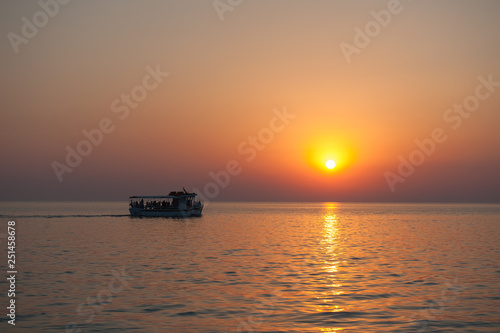 yacht with tourists at sunset with birds flying away © SYARGEENKA