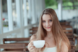 woman holding cup of coffee looking at camera smiling