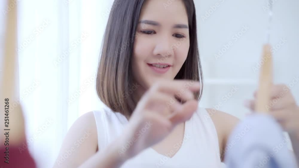 Beautiful attractive young Asian woman choosing her fashion outfit clothes in closet at home or store. Girl think what to wear sweater. Home wardrobe or clothing shop changing room. Beautiful attractive young Asian woman choosing her fashion outfit clothes in closet at home or store. Girl think what to wear sweater. Home wardrobe or clothing shop changing room.