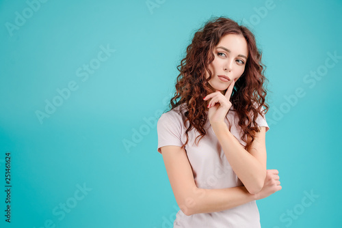 Obraz na plátne Attractive brunette girl with curly hair isolated over blue turquoise background