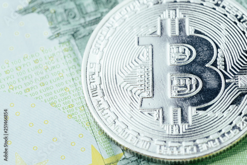 Close up of Bitcoin physical coin with scratch on Euro banknotes using as bear market or profit and loss in crypto currency or new world of financial concept