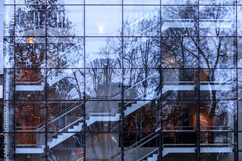 Modern architecture glass façade with indoors construction and stairs  reflecting trees in the park. Nature vs urban. Belgrade, Serbia. Abstract image pictures