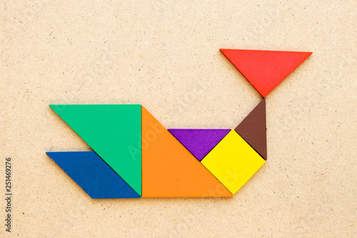 Color tangram puzzle in shark or whale shape on wood background