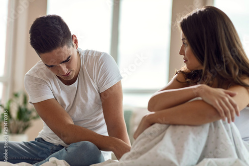 Young unhappy couple having relationship problems in bedroom.