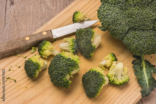 Fresh broccoli and knife on wooden table close up