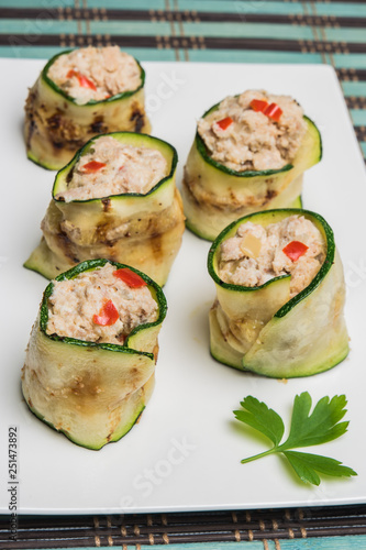 Grilled zucchini rolls with curd cheese and tuna on plate.