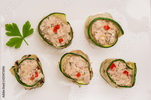 Grilled zucchini rolls with curd cheese and tuna on plate.