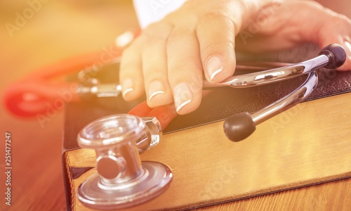 hand with stethoscope on top of old book