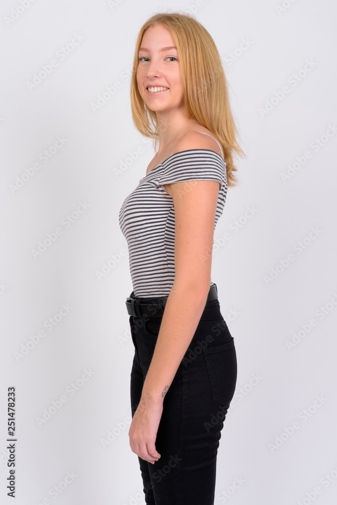 Profile view of happy young beautiful blonde teenage girl smiling at camera Profile view of happy young beautiful blonde teenage girl smiling at camera