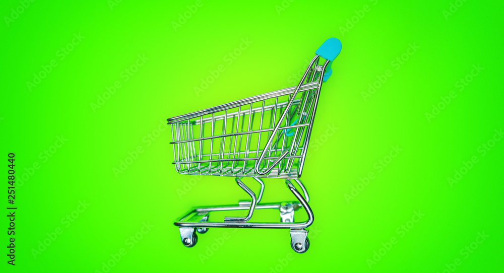 Miniature shopping cart isolated on green Miniature shopping cart isolated on green