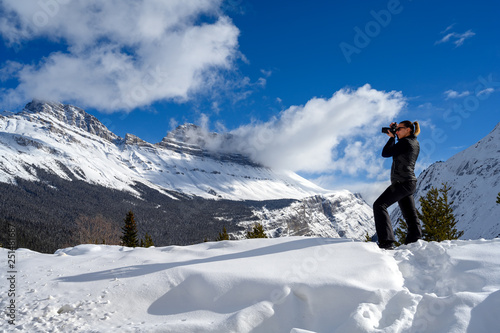 Female nature photographer taking picture of the snowy mountains at the Icefields Parkway in Jasper National, Alberta, Canada