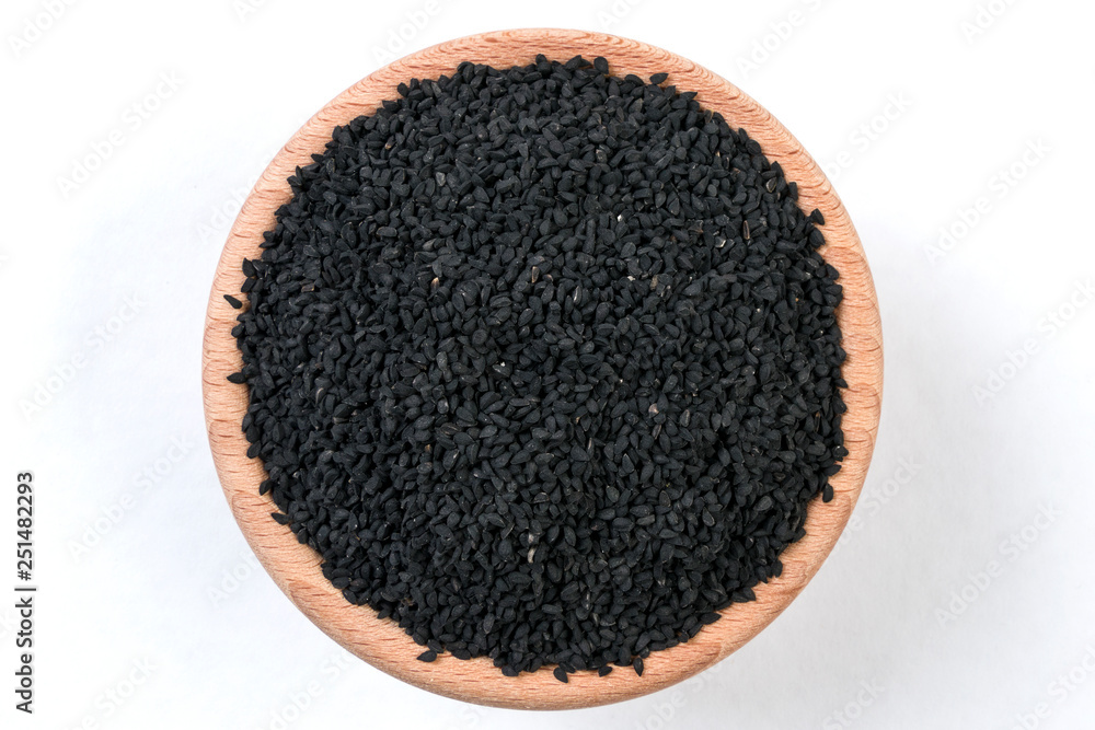 nigella seeds in wooden bowl isolated on white background. nigella seeds in wooden bowl isolated on white background.