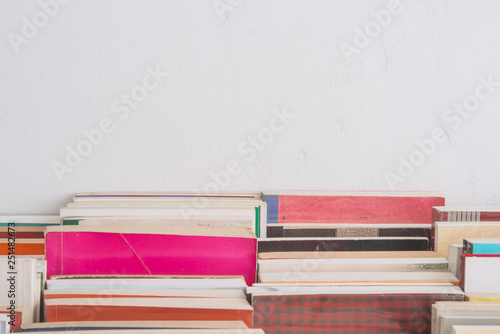 Stack of many old books on table in book store or library room with white wall background and copy space. Knowledge learning  education  bachelor degree in university or back to school concept.
