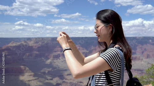 college girl student standing at Grand Canyon viewpoint holding smartphone recording travel trip video turning round wants to memory this beautiful moment. young smiling girl love hiking nature wild. photo