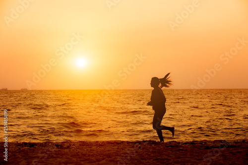 silhouette of woman running on the beach at sunset