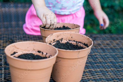 Little girl is putting seeds to soil in a garden