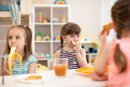 Funny children eating healthy food. Kids lunch at daycare or kindergarten.