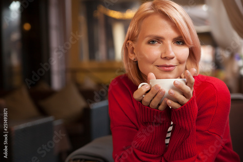 young beautiful girl drinks tea from a white mug, young blonde drinks coffee in a cafe, outdoor cafe