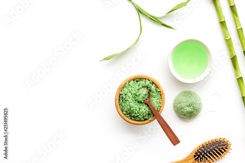 Asian spa treatment concept with natural ingredients. Spa salt, lotion, sponge near bamboo on white background top view copy space