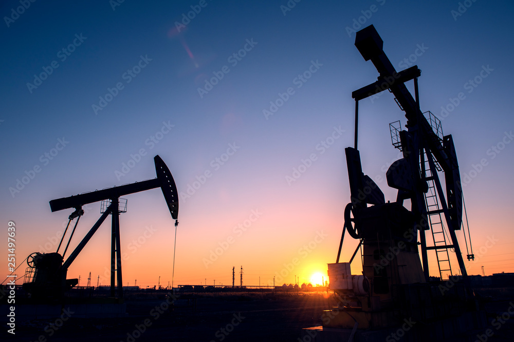 Oil pumps are running in the sunset at the oil field. The outline of the pumping unit. Oil pumps are running in the sunset at the oil field. The outline of the pumping unit.