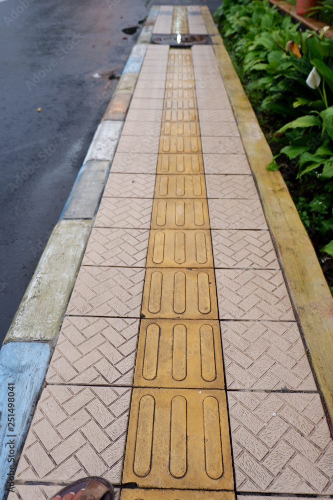 sidewalk with yellow tiles in the middle