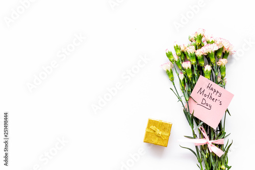 Mother's Day congratulations. Carnations and gift box on white background top view space for text
