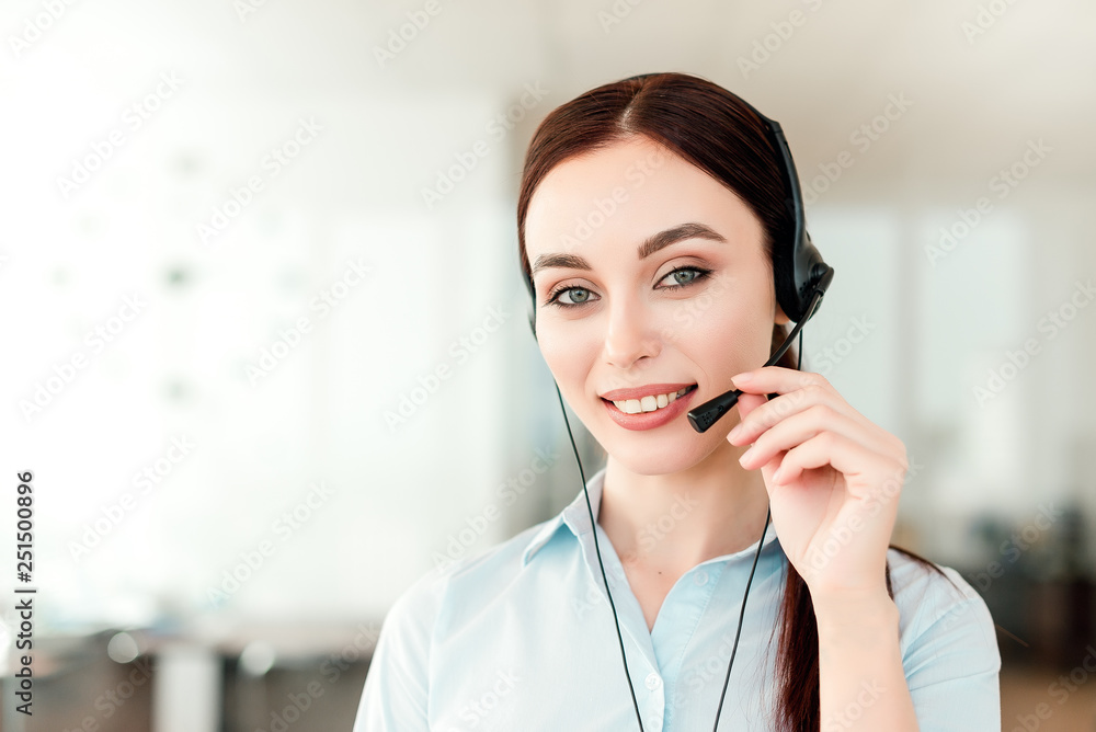Friendly young female technical support dispatcher with a headset working in a call center on a hotline, talking on the phone. Portrait of an attractive customer care representative. Business concept Friendly young female technical support dispatcher with a headset working in a call center on a hotline, talking on the phone. Portrait of an attractive customer care representative. Business concept