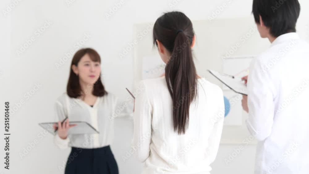 先輩社員のプレゼンテーションを熱心に聞く女性社員 先輩社員のプレゼンテーションを熱心に聞く女性社員
