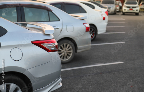 Closeup of back or rear side of blue car and other cars parking in parking area of public park in twilight evening. 