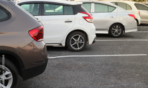 Closeup of back or rear side of brown car and other cars parking in parking area in twilight evening. 