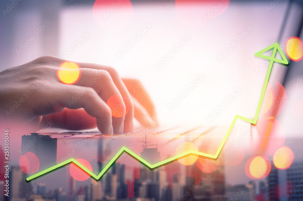 Woman hand using keyboard laptop double exposure of blur building city and up trend green graph trade with colorful bokeh abstract background. Woman hand using keyboard laptop double exposure of blur building city and up trend green graph trade with colorful bokeh abstract background.