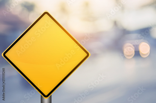 Fotografia Empty yellow traffic sign on blur traffic road with colorful bokeh light abstract background