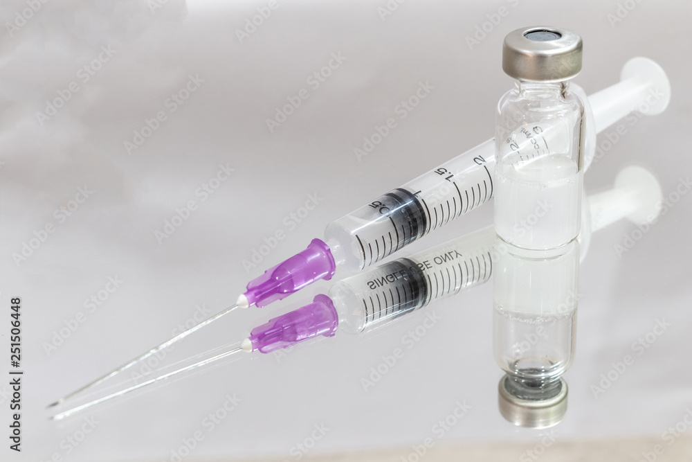 Vials with medication and injection needle on mirror. Vials with medication and injection needle on mirror.
