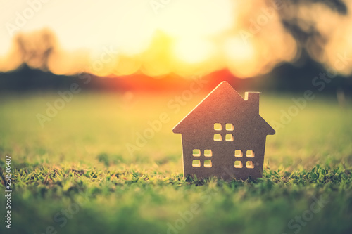 Copy space of home and life concept. Small model home on green grass with sunlight abstract background. photo