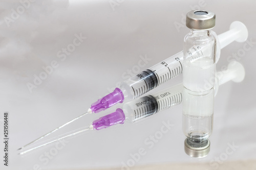 Vials with medication and injection needle on mirror.