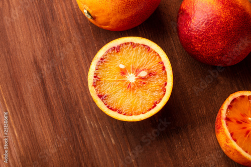 A closeup photo of an organic blood orange on a dark rustic wooden background with a place for text