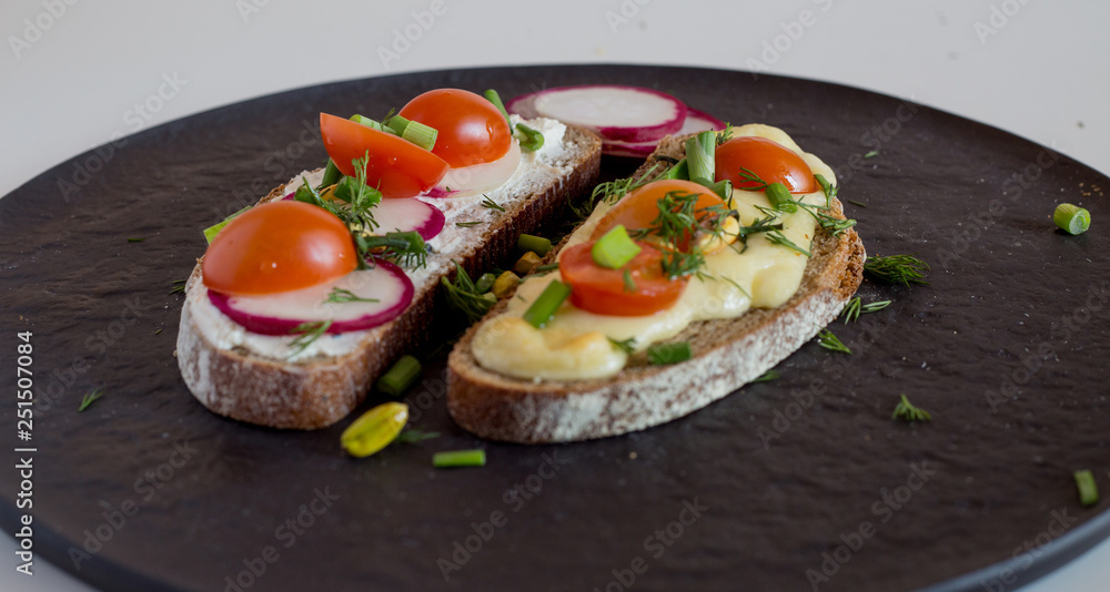 Multigrain toast bread with melt gouda or kaseri cheese and small tomatoes radish and green onion on top Multigrain toast bread with melt gouda or kaseri cheese and small tomatoes radish and green onion on top